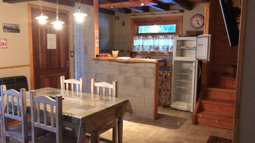 cocina con mesa, sillas y nevera en Mi lugar en Villa La Angostura