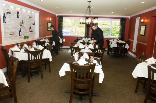 a dining room with tables and two men standing in a restaurant at Restland Motel in Clarenville