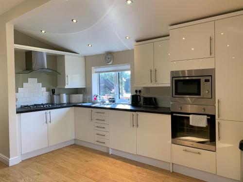 a kitchen with white cabinets and a stove top oven at Owls House - Lodge with hot tub- Lake District in Windermere