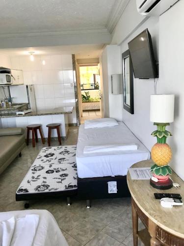 a bedroom with a bed and a table and a kitchen at Flat Vista Mar Frente ou Lateral na Barra em Salvador in Salvador