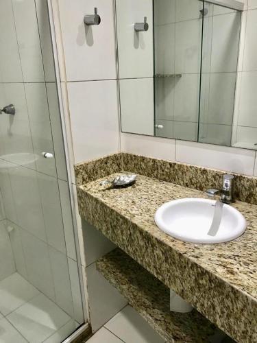 a bathroom with a sink and a glass shower at Flat Vista Mar Frente ou Lateral na Barra em Salvador in Salvador