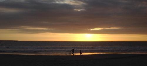 two people walking on the beach at sunset at Casa Killa Vichayito in Vichayito