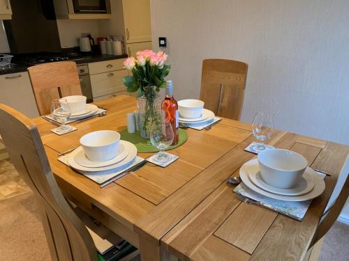 a wooden table with plates and bowls and flowers on it at Tiggywinkle Beck Lodge in Windermere