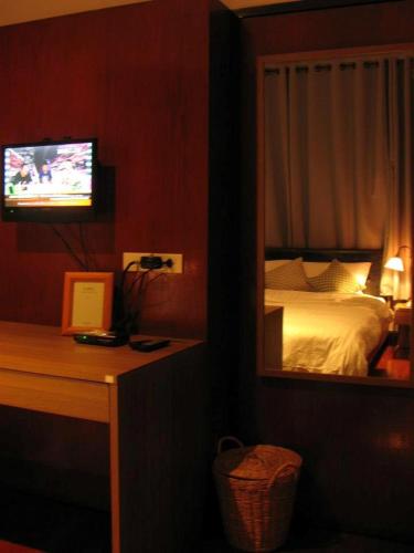 a bedroom with a bed with a mirror and a television at House 23 Guesthouse in Bangkok