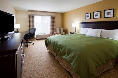 a hotel room with a bed and a flat screen tv at Country Inn & Suites by Radisson, Minot, ND in Minot