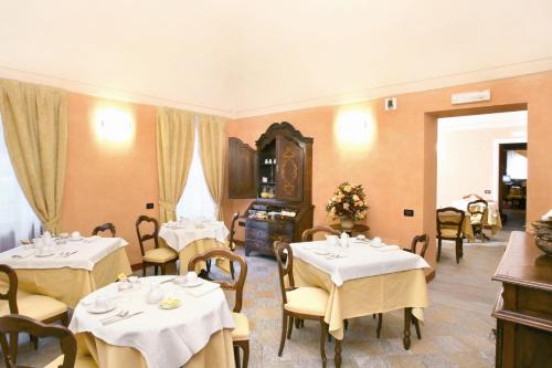 ein Restaurant mit Tischen und Stühlen mit weißem Tischtuch in der Unterkunft Hotel Palazzo Di Mezzo in Carrù