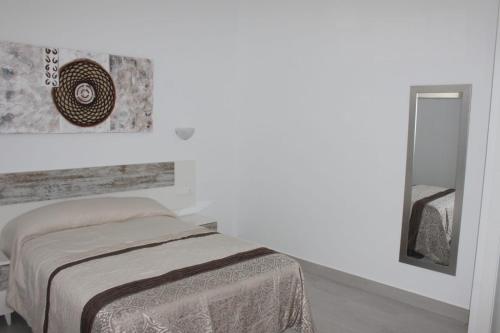 Habitación blanca con cama y espejo en Apartamentos Margo 2, en Málaga