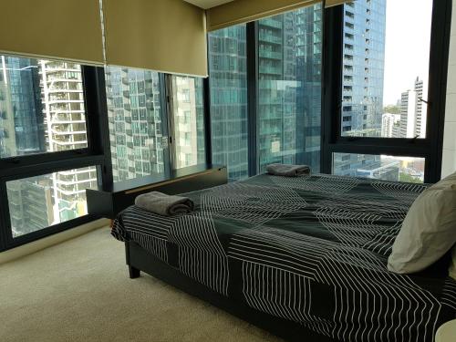a bedroom with a large bed with large windows at ReadySet Apartments at Southbank One in Melbourne