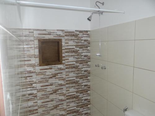 a bathroom with a shower with a stone wall at Pousada Canto dos Canários in Socorro