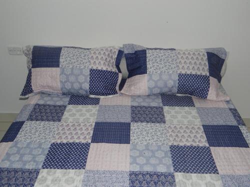 a bed with pillows and a blue and white quilt at Pousada Canto dos Canários in Socorro