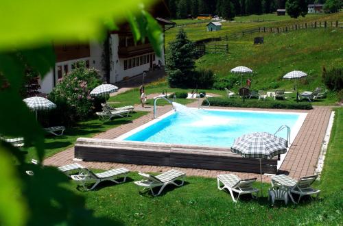 a swimming pool with chairs and umbrellas in a yard at Familienhotel Lengauer Hof in Saalbach Hinterglemm