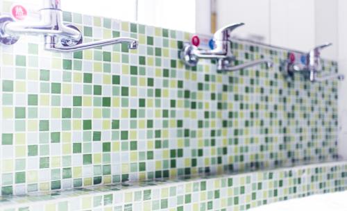 a bathroom with two faucets and green and white tiles at 大连天天青旅民宿 in Dalian