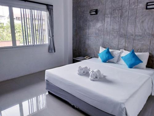 a bedroom with a large white bed with blue pillows at Bun Hotel in Surat Thani