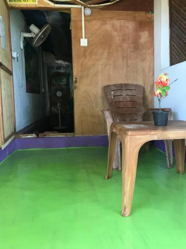 a table and a chair in a room with a green floor at Star Rest Beach Hotel in Arugam Bay