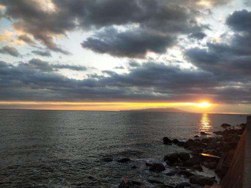 a sunset over a body of water with rocks at Izu Hokkawa Seaside Guesthouse 伊豆北川の家 in Higashiizu
