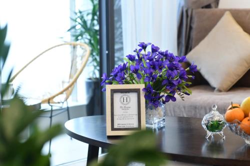 a table with a vase of purple flowers on it at Hi-Home Suites - Vinhomes Metropolis in Hanoi