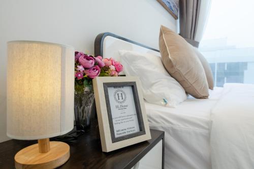 a picture frame on a table next to a bed with flowers at Hi-Home Suites - Vinhomes Metropolis in Hanoi