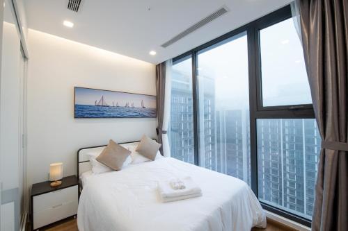 a bedroom with a white bed and a large window at Hi-Home Suites - Vinhomes Metropolis in Hanoi