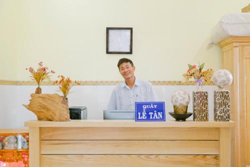 Ein Mann steht hinter einer Theke mit einer blauen Schachtel. in der Unterkunft Nhà Nghỉ Quê Ló in Long Hải
