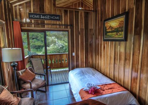 um quarto com uma cama e um cartaz que lê a casa noturna em Cabañas Hoja Verde em Monteverde
