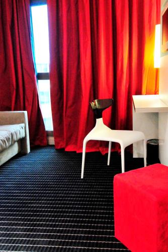 a red room with a chair and a red curtain at Résidence Ôtelia Affaires & Bien-être in Lyon