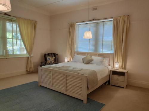 a bedroom with a bed and a chair and windows at Lake House Benalla in Benalla