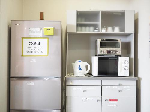 a kitchen with a refrigerator and a microwave at Shin-Osaka Youth Hostel in Osaka
