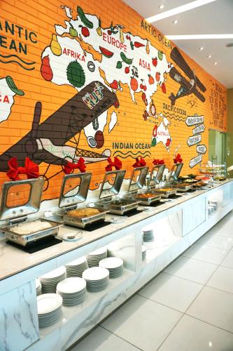 a buffet line with plates of food in a restaurant at Zest Airport Jakarta by Swiss-Belhotel International in Tangerang