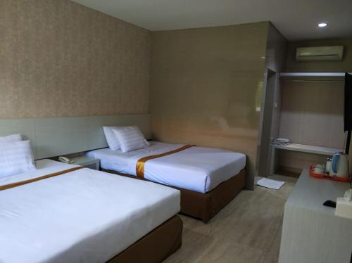 Hotel Sinar 2 في Sedati: غرفه فندقيه سريرين وتلفزيون