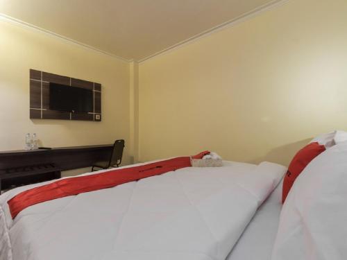 a bedroom with two beds and a tv on the wall at RedDoorz Plus at Boulevard Panakkukang Makassar in Makassar