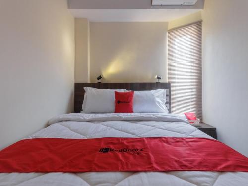 a bedroom with a large bed with a red blanket at RedDoorz Plus at Boulevard Panakkukang Makassar in Makassar