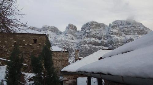 a mountain covered in snow next to a building at Morfeas Guesthouse in Papigko