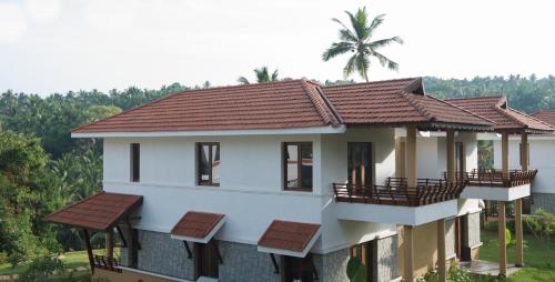 a white house with a red roof at Niraamaya Wellness Retreats, Surya Samudra, Kovalam in Kovalam