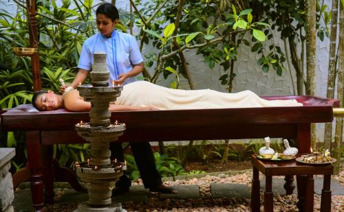 a woman giving a man a massage on a bed at Niraamaya Wellness Retreats, Surya Samudra, Kovalam in Kovalam