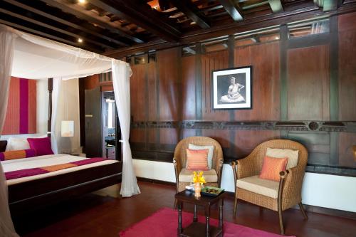 a bedroom with a canopy bed and two chairs at Niraamaya Wellness Retreats, Surya Samudra, Kovalam in Kovalam