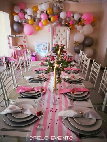 Jane FurseにあるNALEDI LODGE & GUEST HOUSESのピンクと黒の皿とグラスが置かれた長いテーブル