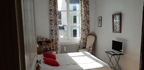 Un dormitorio con una cama con almohadas rojas y una ventana en Chambre d'Hôtes Marchand, en Angers