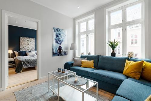 a living room with a blue couch and a bed at Høyden Apartments in Bergen