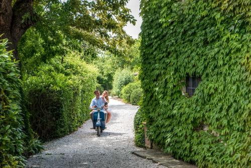 two people are riding a bike down the street at Monsignor Della Casa Country Resort & Spa in Borgo San Lorenzo