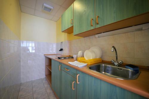 a kitchen with green cabinets and a sink at Panorama Hotel Noszvaj in Noszvaj