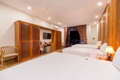 Cette chambre comprend deux lits et une télévision. dans l'établissement Phong Phu Villa Hoi An, à Hội An