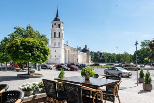a table and chairs in front of a building with a tower at Amberton Cathedral Square Hotel Vilnius in Vilnius