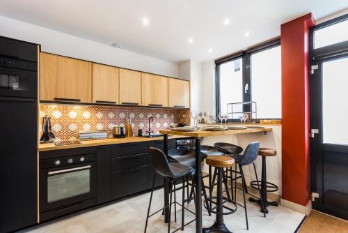 a kitchen with black cabinets and bar stools at CMG Nation/ Vincennes II in Paris