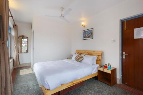 a bedroom with a white bed and a wooden door at Pacific Guest House in Kathmandu