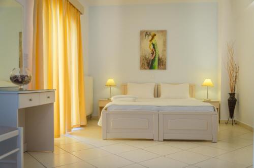 スカラ・ポタミアスにあるErics Apartmentの白いベッドと黄色のカーテンが備わる白いベッドルーム1室