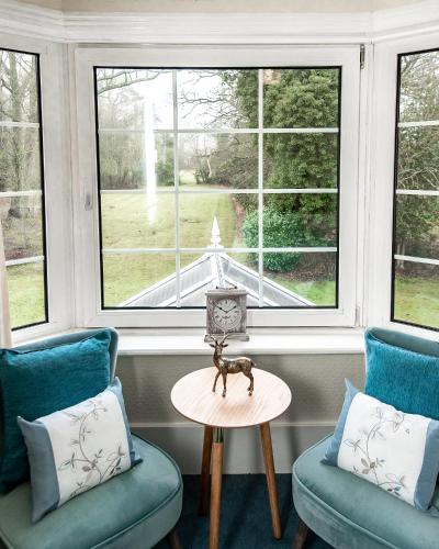 a room with two chairs and a table and windows at Trivelles Waterhall Country Gatwick Hotel & airport parking in Crawley