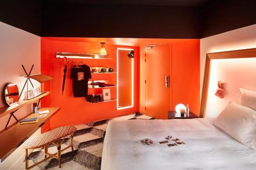 a bedroom with orange walls and a bed and a chair at Mama Shelter Toulouse in Toulouse