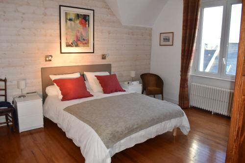una camera da letto con un grande letto con cuscini rossi di Maison spacieuse entre la ville et la côte a Saint-Martin-des-Champs