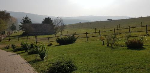 a grassy field with a fence and a house at Bársonyberek vendégház Bakony in Jásd