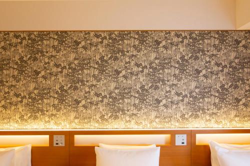 a wall with a floral pattern on it next to two beds at karaksa hotel grande Shin-Osaka Tower in Osaka